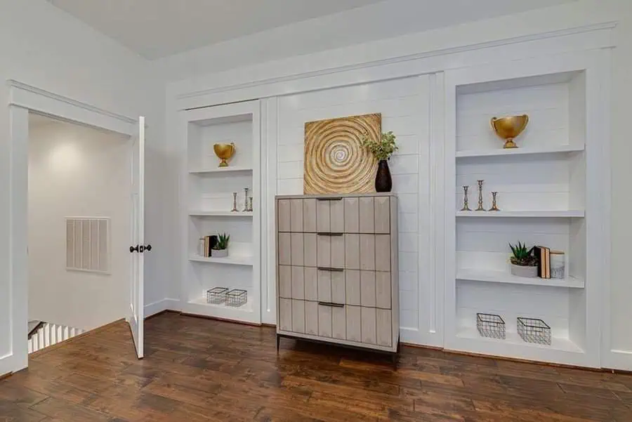 Bright space with built-in white shelves, a modern wood dresser, and warm mixed wood tones.