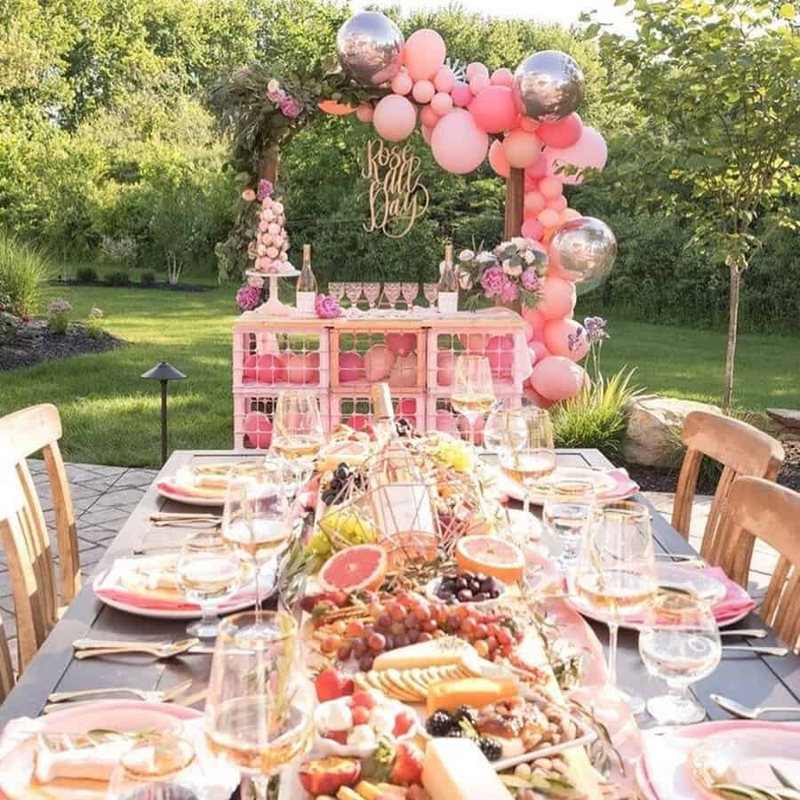 Brunch-style housewarming party with a beautifully set outdoor table, charcuterie, and pink decor.