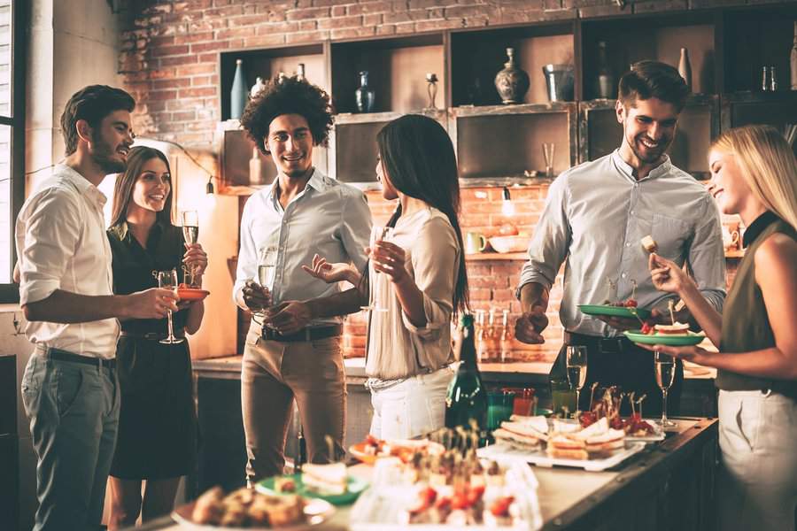 Friends enjoying a housewarming party with drinks, appetizers, and lively conversation.