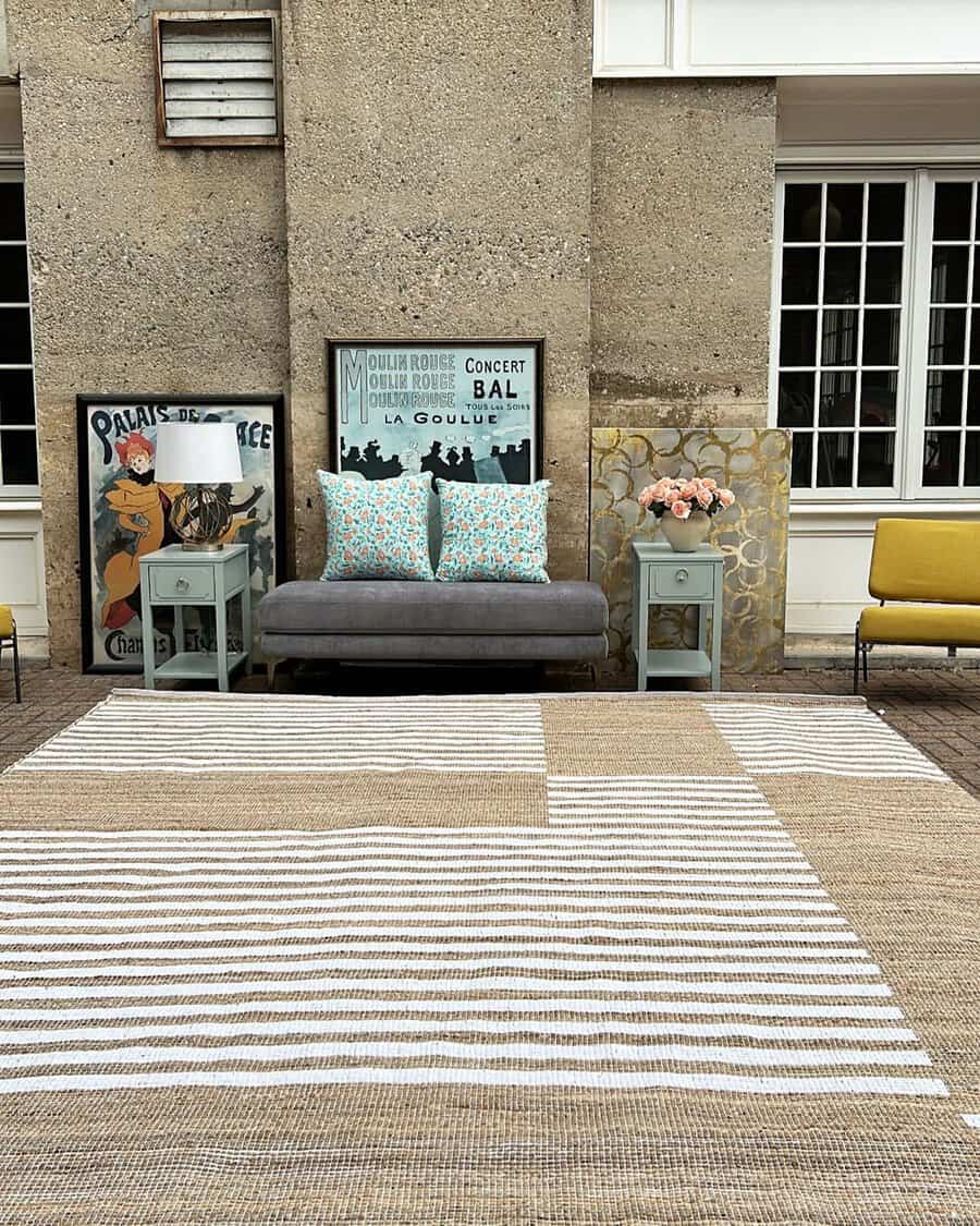 Outdoor-inspired carpeted living space with a striped rug, vintage decor, and eclectic seating.