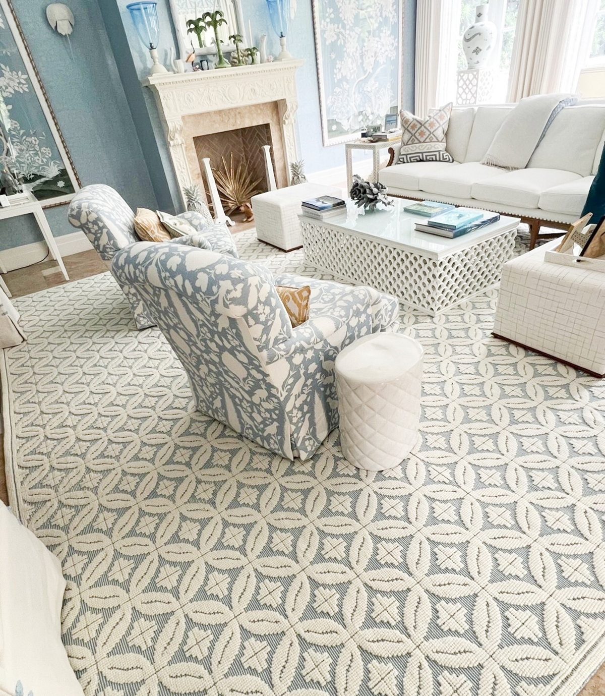 Elegant carpeted living room with blue and white decor, patterned armchairs, and a fireplace.