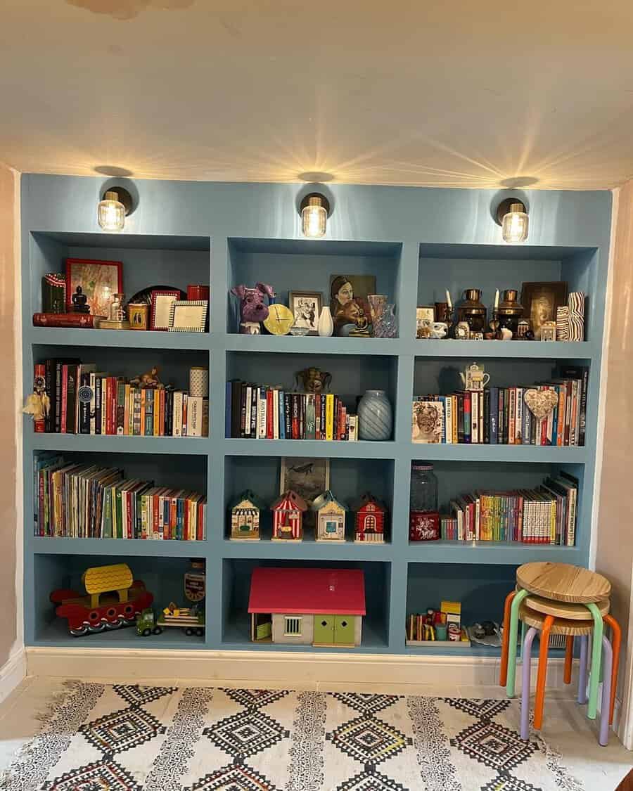 Children's home library with built-in blue bookshelves, playful decor, and warm lighting.