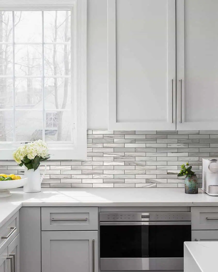 Classic subway tile backsplash enhances white cabinets for a timeless and elegant kitchen design.