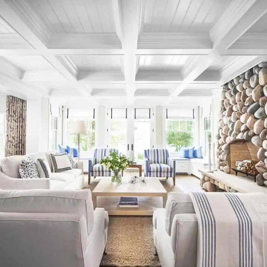 Coastal bedroom with a modern coffered ceiling, soft blue walls, elegant decor, and ocean views.