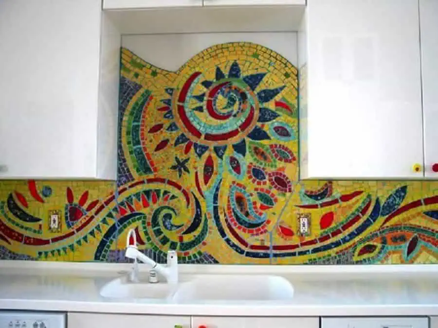 Colorful mosaic tile backsplash adds artistic flair and vibrant contrast to sleek white cabinets.