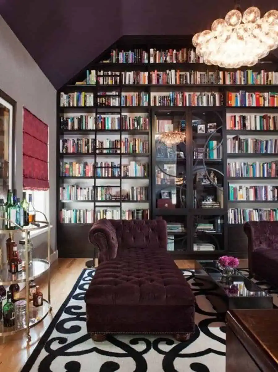 Contemporary living room with glass bookshelves, a velvet chaise lounge, and elegant decor.