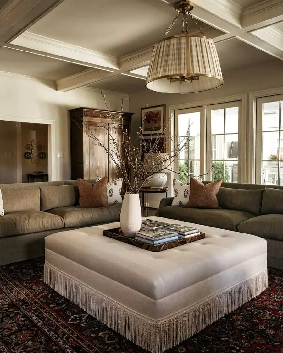 Contemporary living room with a modern coffered ceiling, tufted ottoman, and elegant lighting.