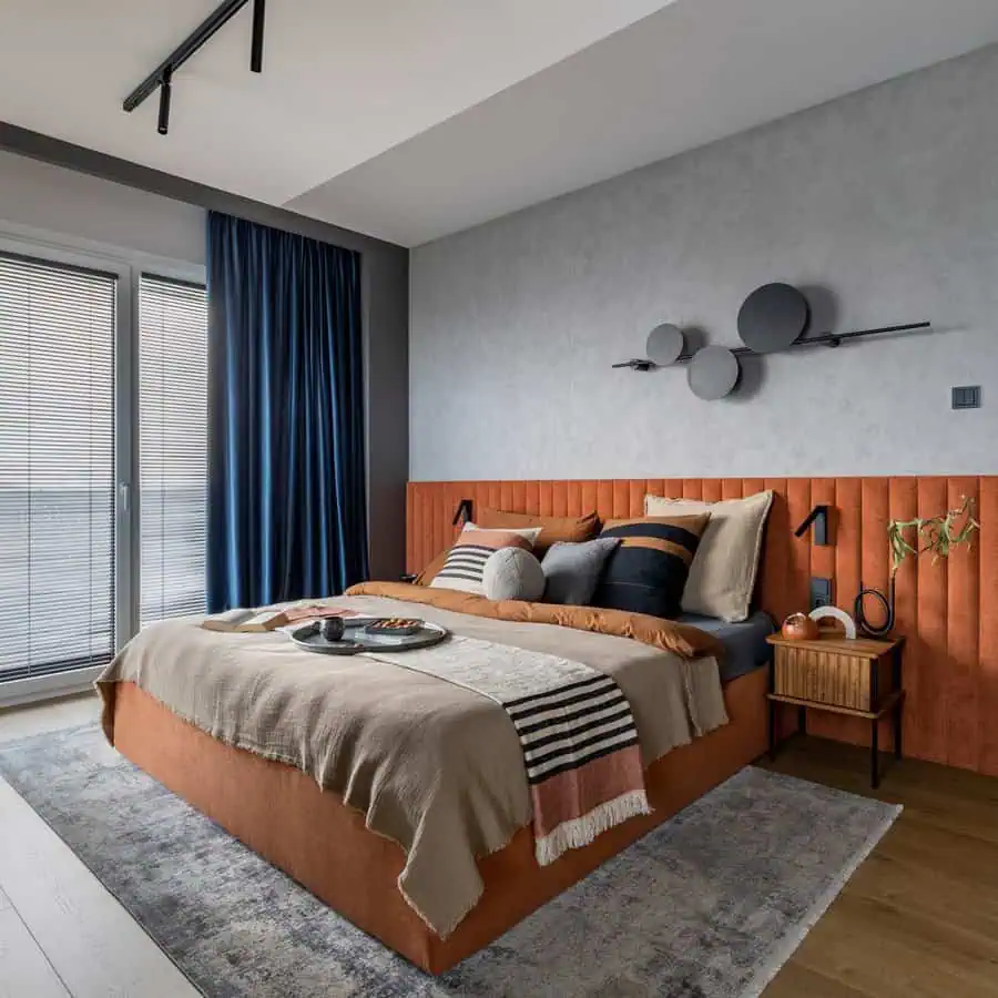 Contemporary orange bedroom with a sleek grey accent wall, modern furnishings, and cozy textures.