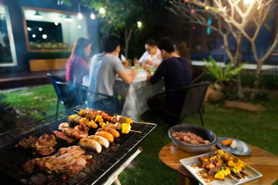 Cozy backyard housewarming party with friends enjoying grilled skewers and a festive outdoor dinner.