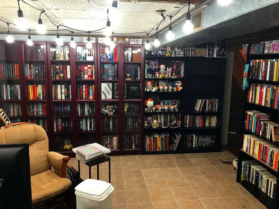 Cozy basement home library with glass-front bookshelves, collectibles, and warm lighting.