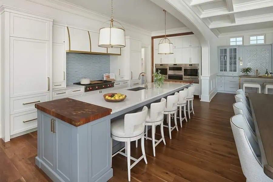 Spacious open kitchen with a large island, white cabinetry, gold accents, and a cozy dining nook.