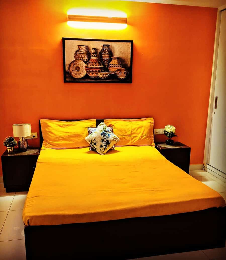 Cozy small orange bedroom with budget-friendly decor, simple furnishings, and warm lighting.