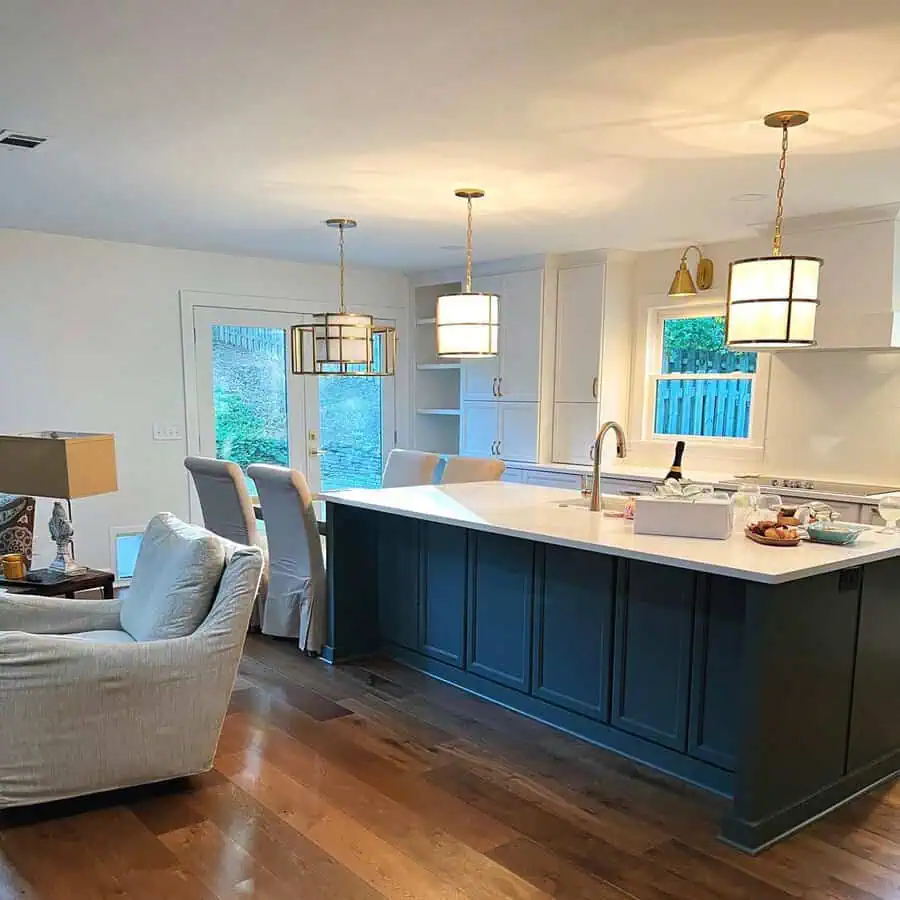 Open kitchen with a deep blue island, white cabinetry, and elegant pendant lighting.