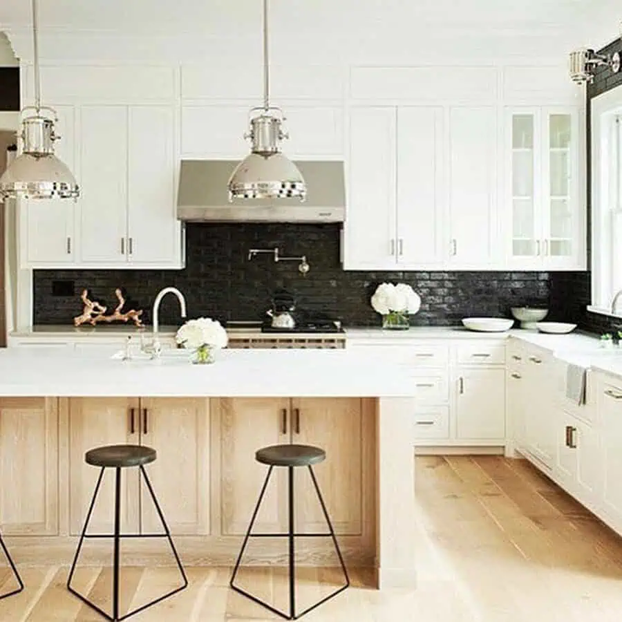 Dark marble backsplash adds dramatic contrast and luxury to white cabinets for a sophisticated kitchen.