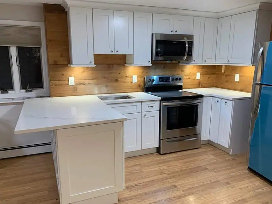 Dark wood-like backsplash adds warmth and contrast to white cabinets for a cozy and inviting kitchen.