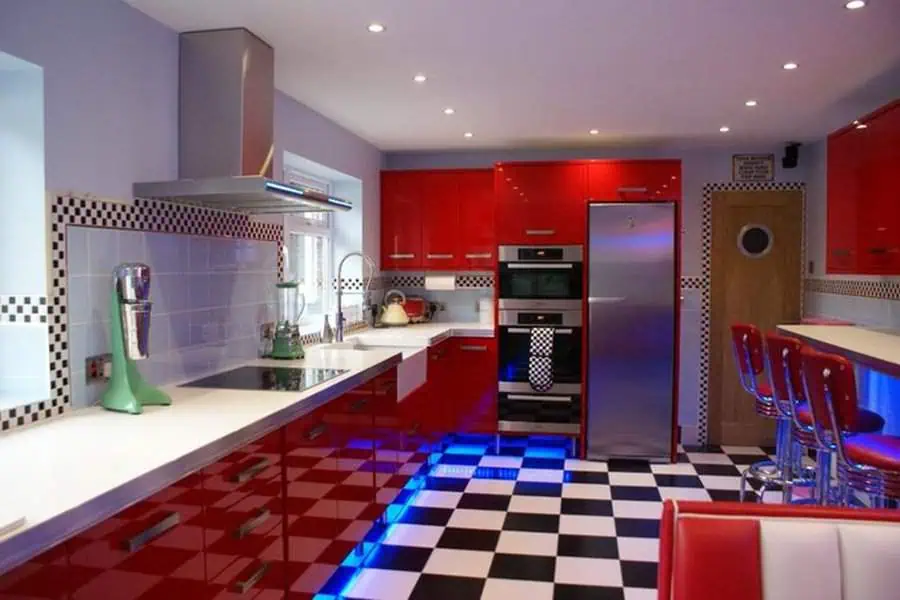 Diner-inspired retro kitchen with bold red cabinets, checkered flooring, and vintage bar stools.