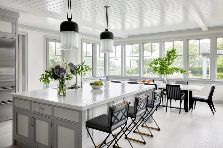Bright open kitchen with a large island, black pendant lights, and a spacious dining area.