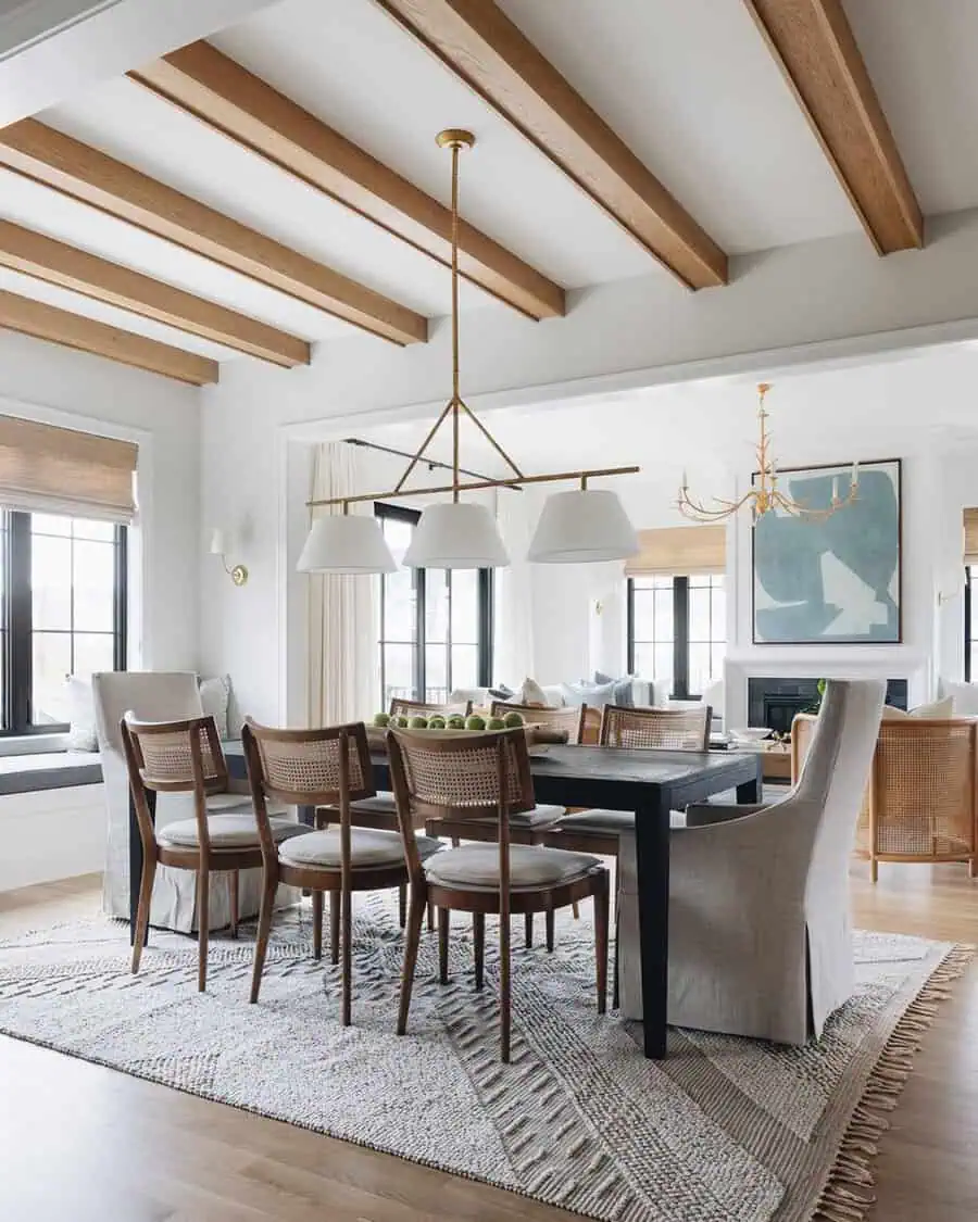 Dining room with wood beam ceiling, black table, woven chairs, and a textured neutral rug.