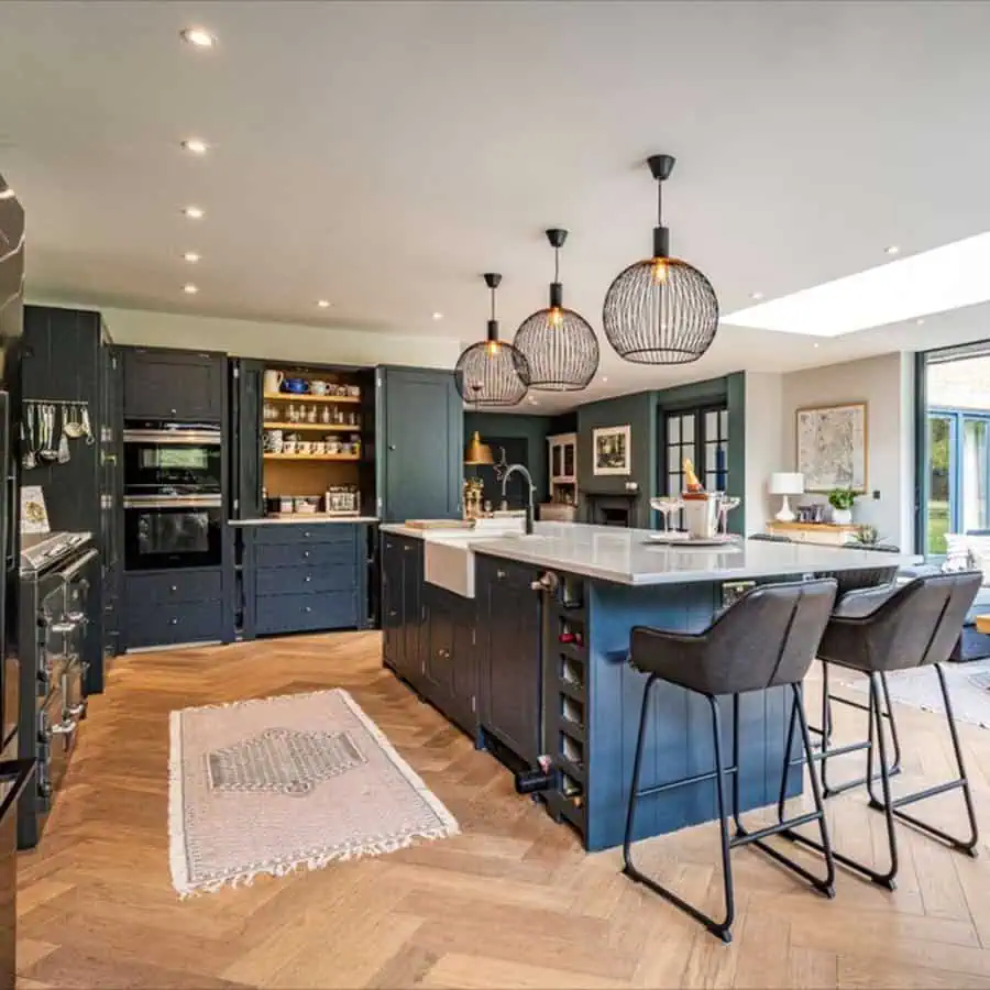 Modern open kitchen with navy cabinetry, a large island, pendant lighting, and a dining extension.