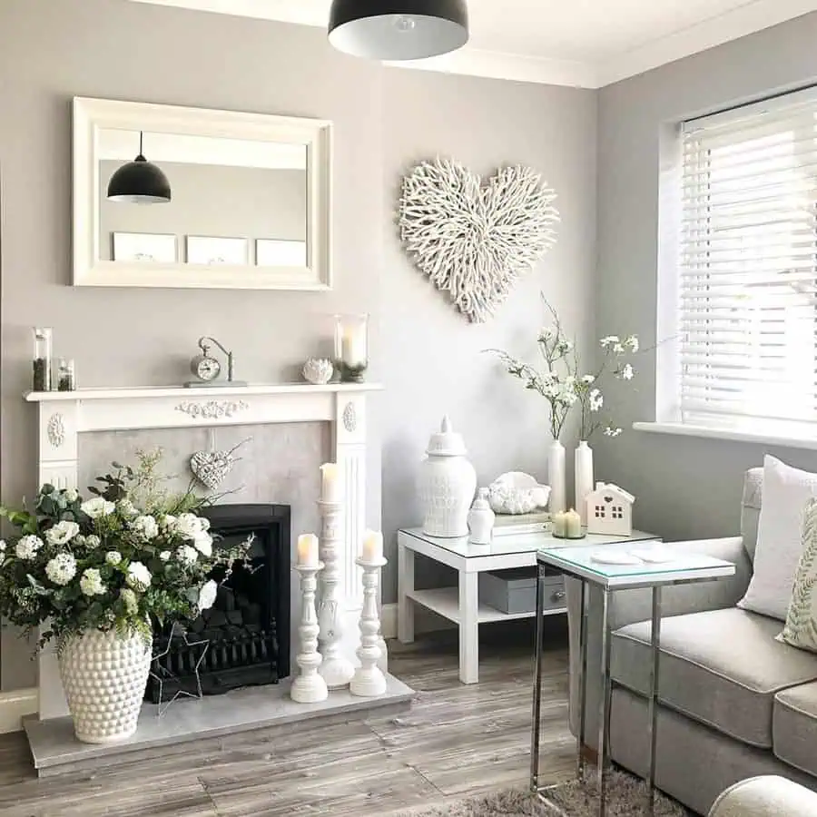 Grey and white living room with a cozy fireplace, elegant decor, and floral arrangements.