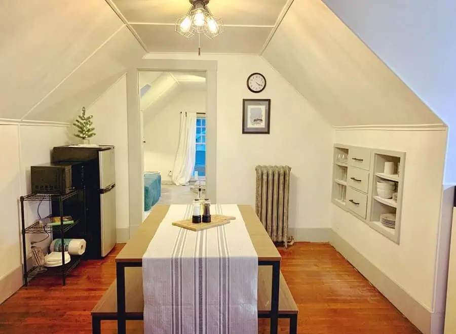 Dutch Colonial farmhouse with a cozy attic dining area, built-in shelves, and wooden floors.