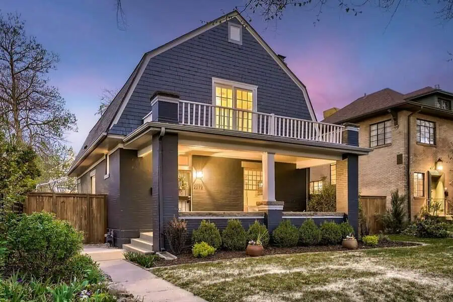 Dutch Colonial-style house with historic design, covered porch, and warm evening lighting.