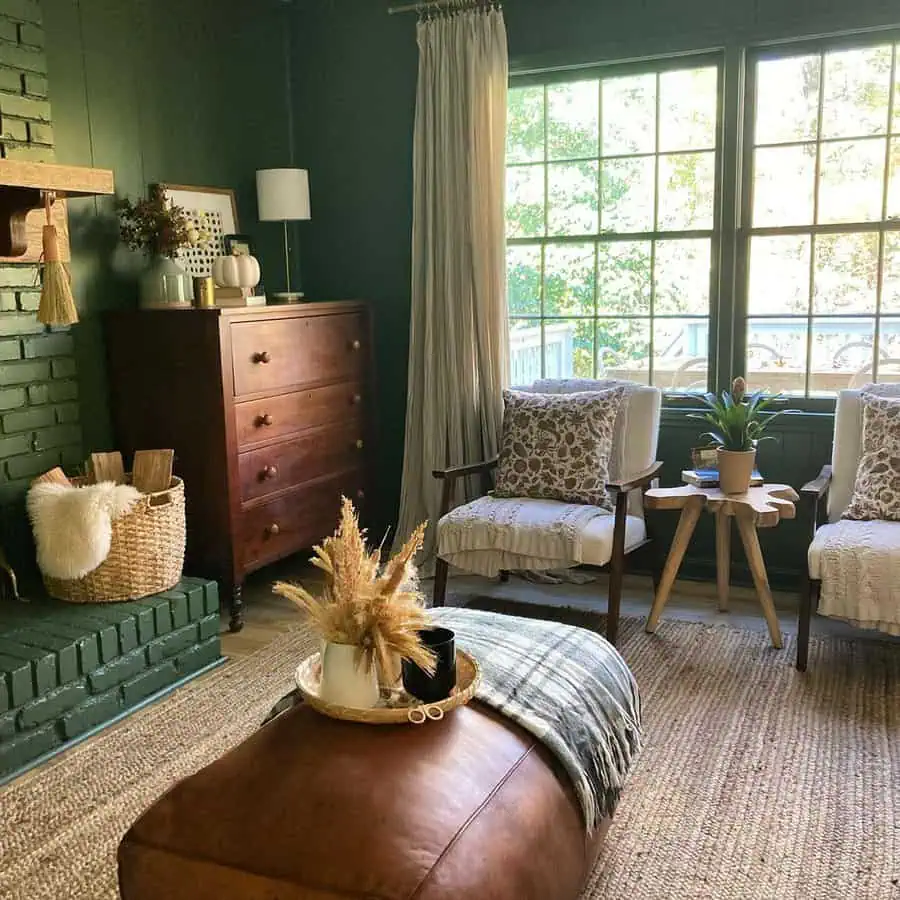 Dutch Colonial Revival interior with green walls, a brick fireplace, vintage wood furniture, and cozy rustic decor.