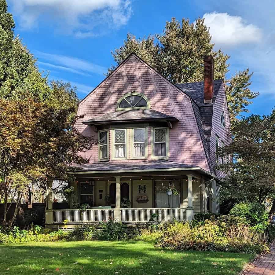 Dutch Colonial Revival house with a wraparound porch, bay windows, and historic charm.