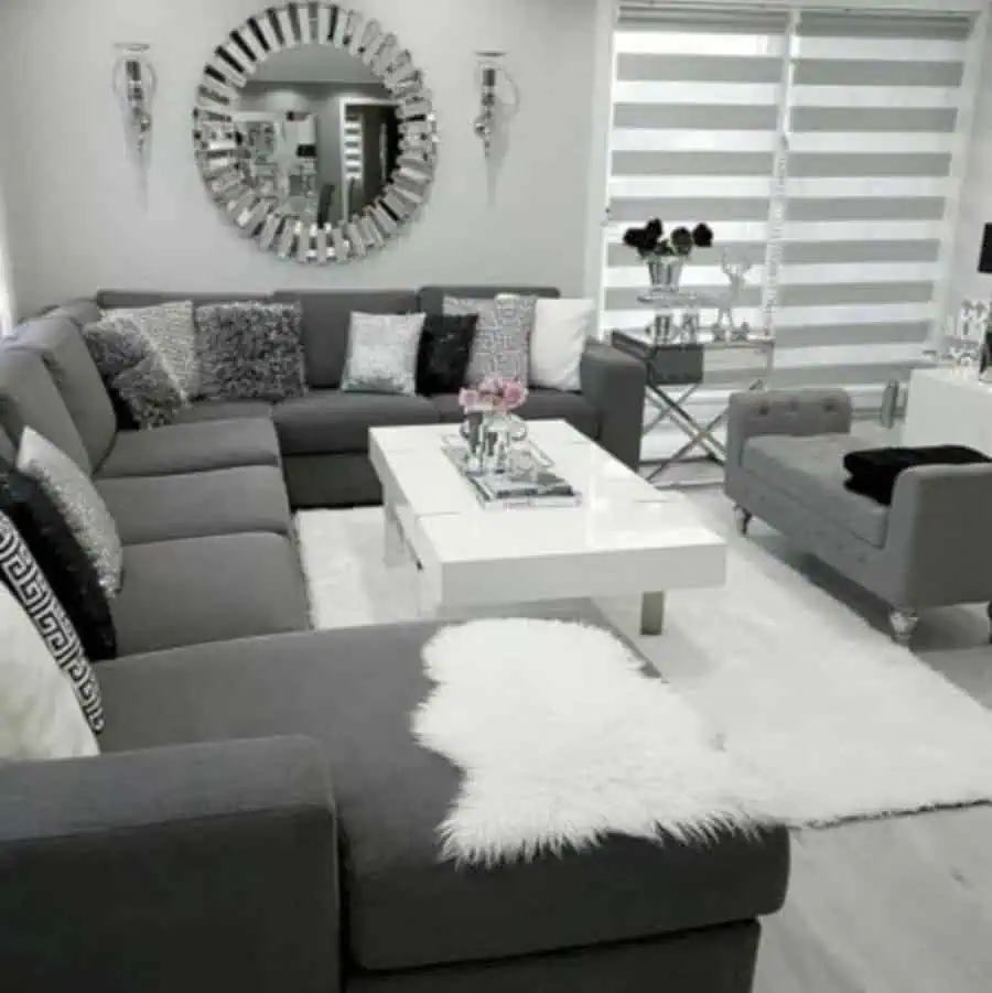 Elegant grey and white living room with a sectional sofa, mirrored wall decor, and a modern coffee table.