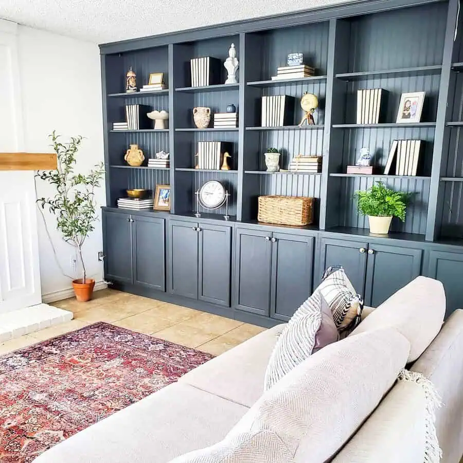 Elegant home library with navy built-in bookshelves, decorative accents, and a cozy sofa.