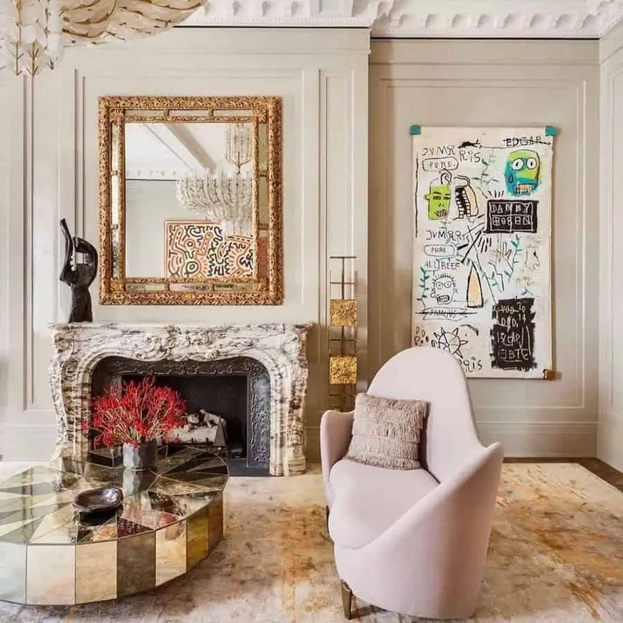 Elegant gold-framed mirror above a marble mantel with a modern art piece and chic decor.