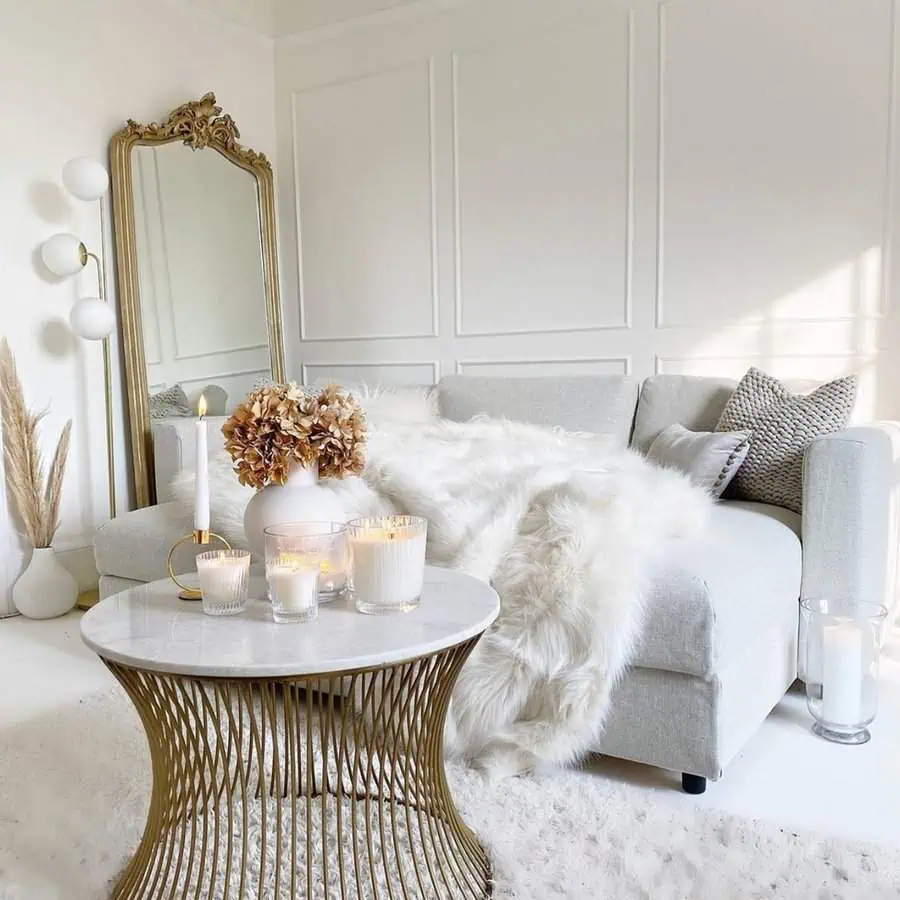 Ornate gold-framed mirror in a cozy living room with soft textures and warm candlelight.