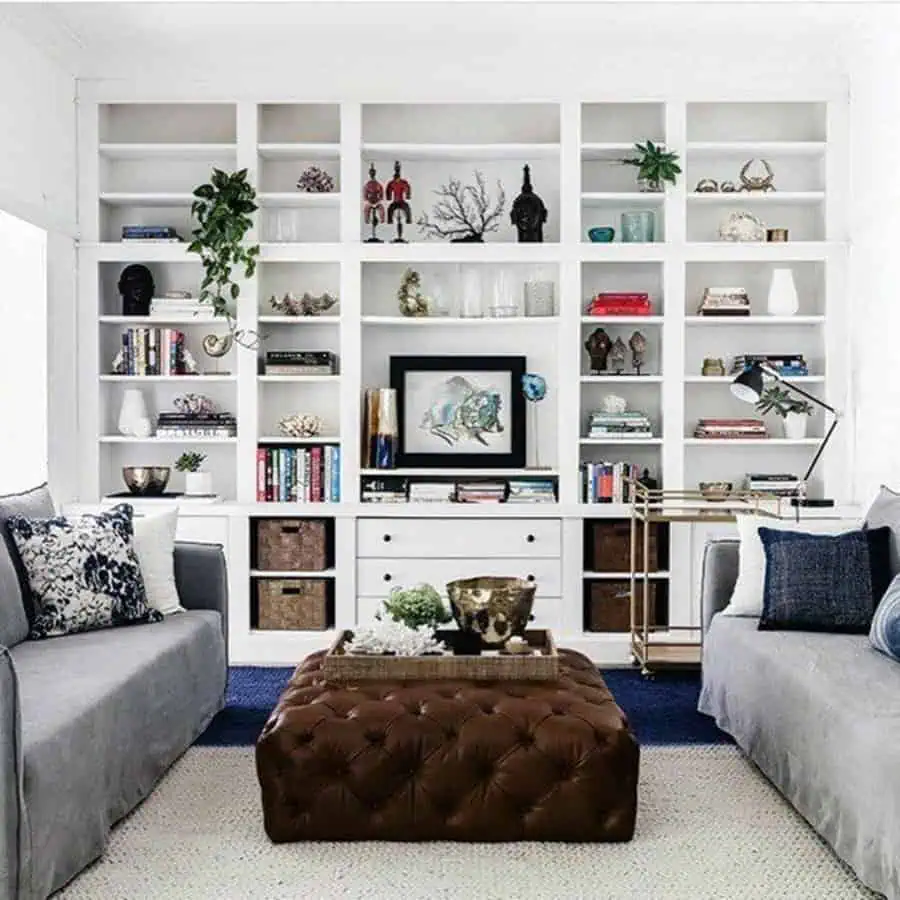 Modern living room with a white floor-to-ceiling bookshelf, decorative accents, and cozy seating.