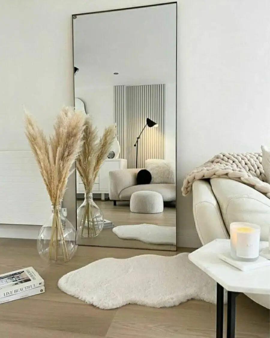 Full-length mirror reflecting a cozy, minimalist living room with soft textures and plants.