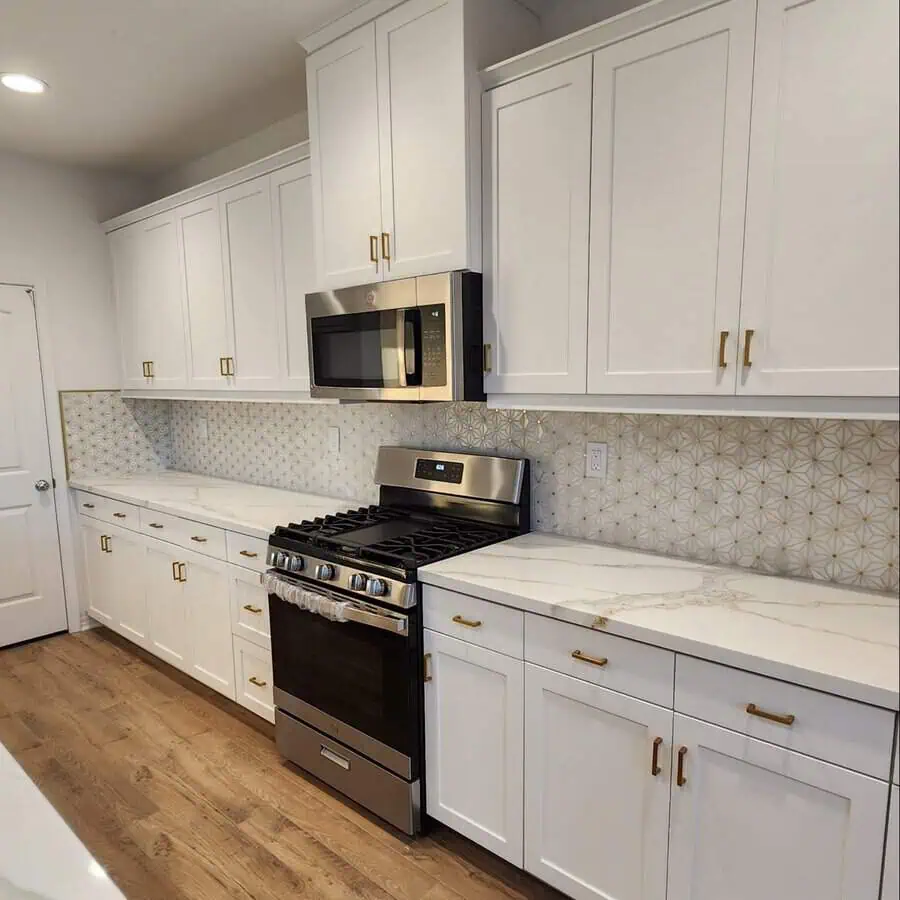 Geometric mosaic tile backsplash adds artistic flair and sophistication to white cabinets.