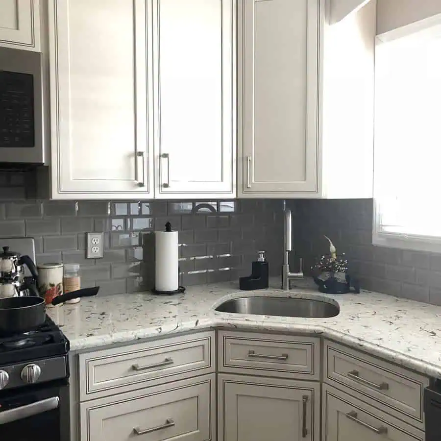 Glossy gray subway tile backsplash contrasts with white cabinets for a sleek, modern kitchen look.