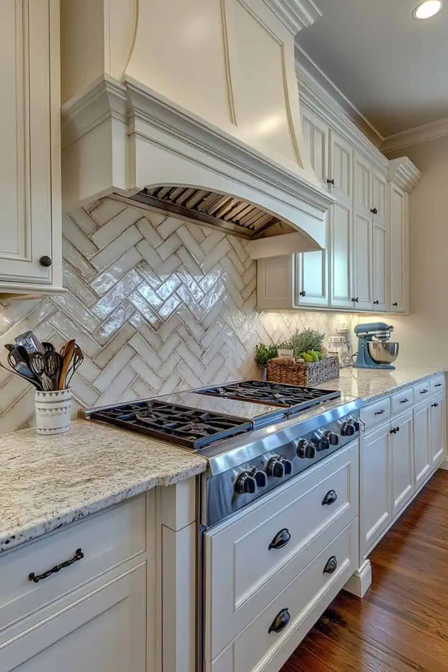 Glossy herringbone tile backsplash enhances white cabinets for a vintage-inspired, elegant kitchen.