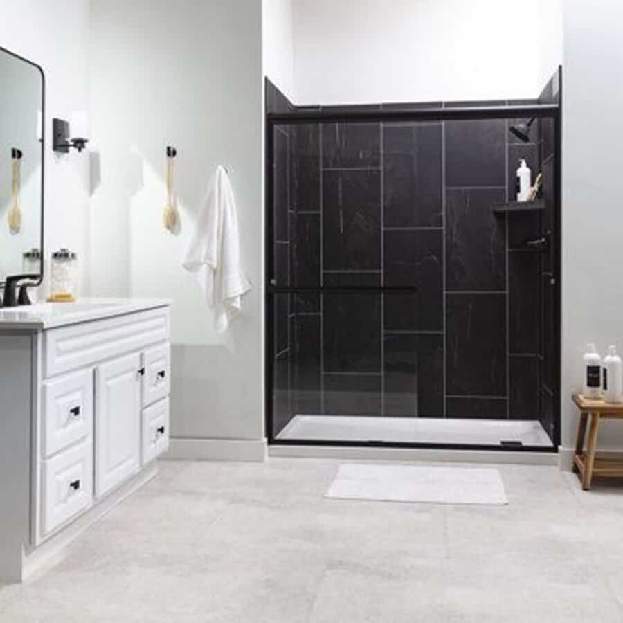 Black and white bathroom with a glossy black tile shower enclosure and white vanity.