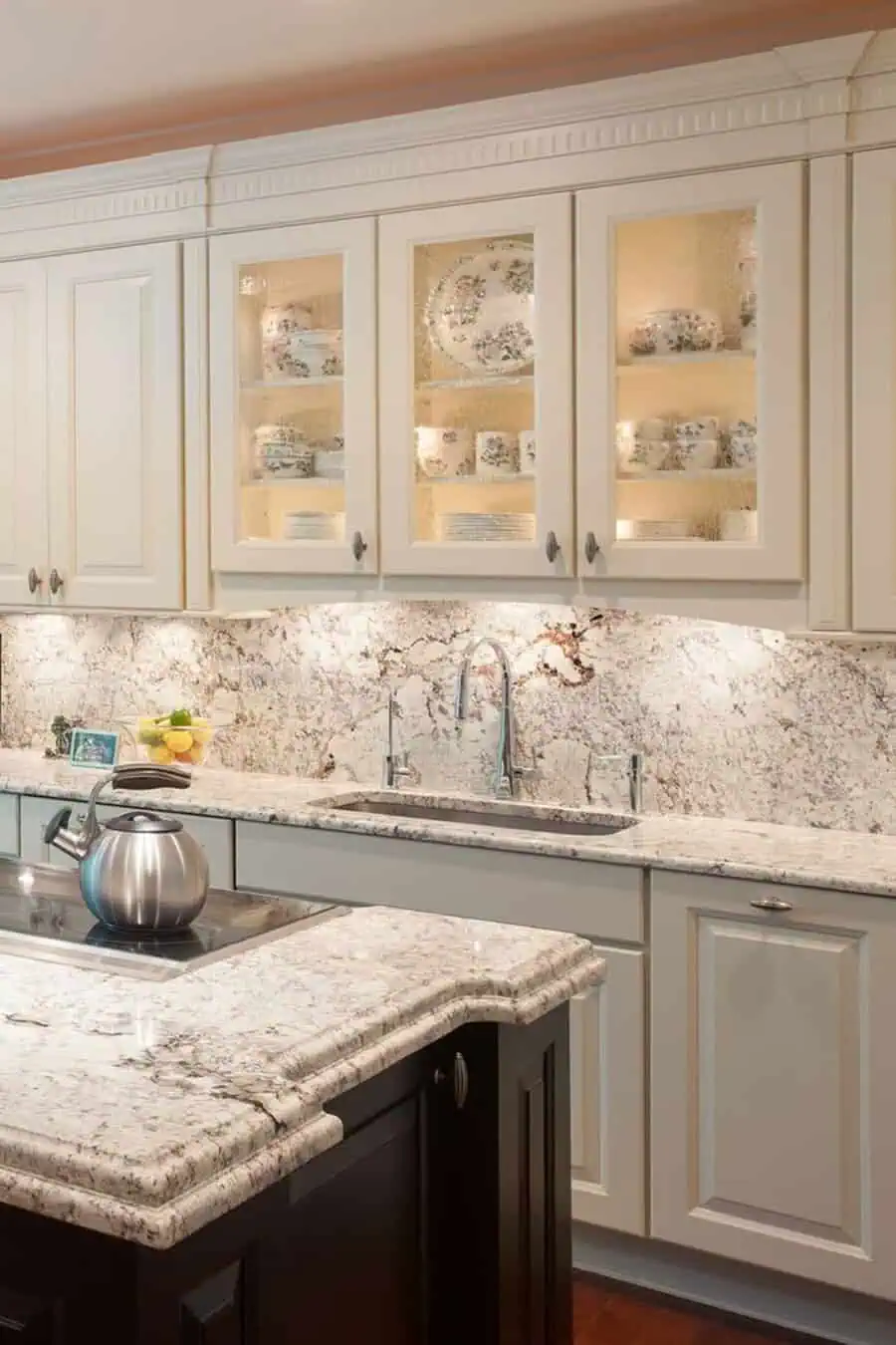 Granite backsplash and matching countertop enhance white cabinets for a seamless, elegant kitchen look.