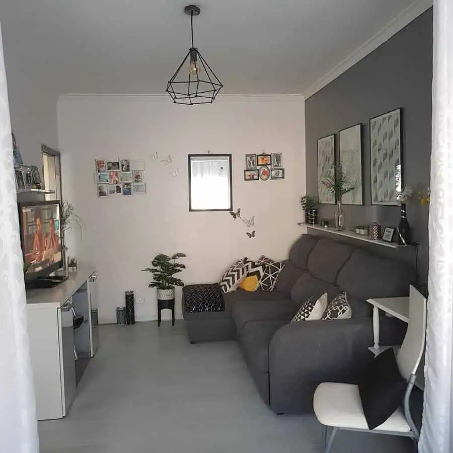 Grey and white living room with a cozy sofa, wall decor, houseplants, and a geometric pendant light.