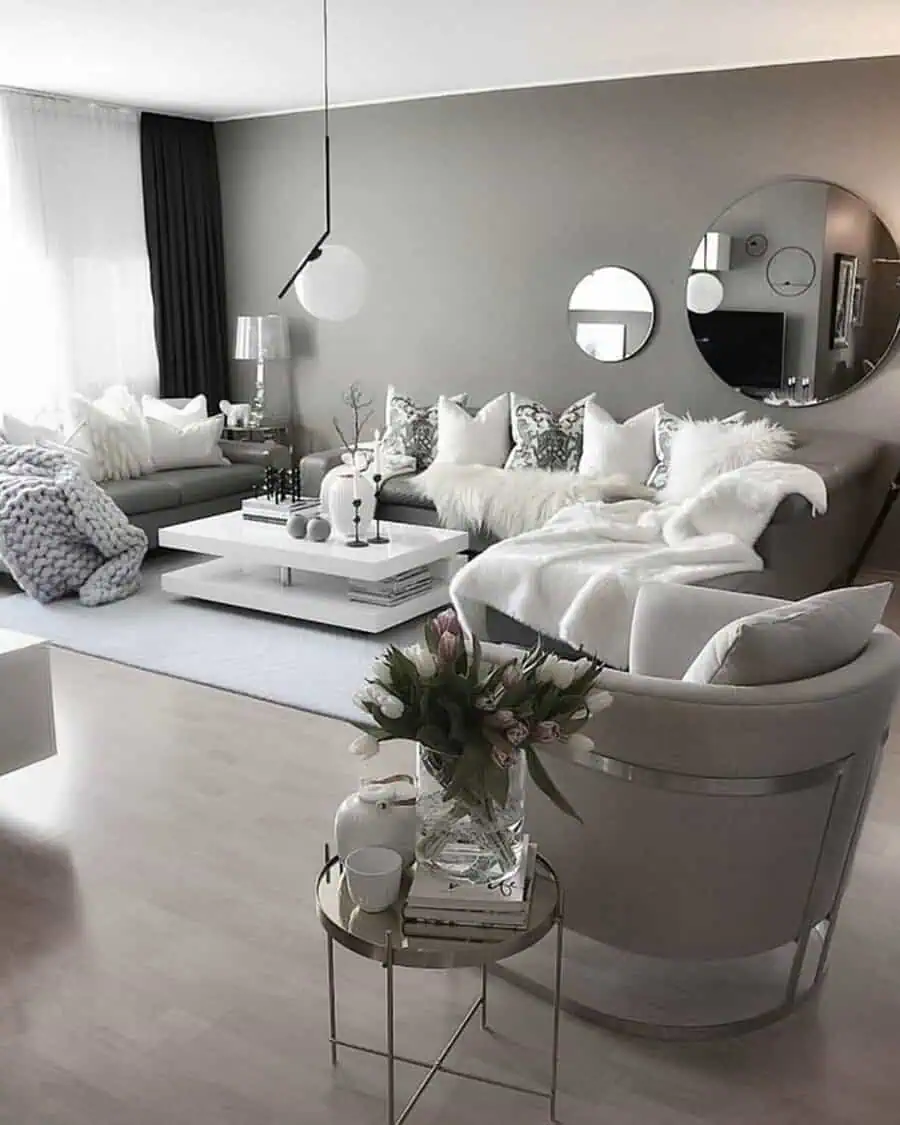 Sophisticated grey and white living room with plush seating, modern mirrors, and cozy decorative accents.