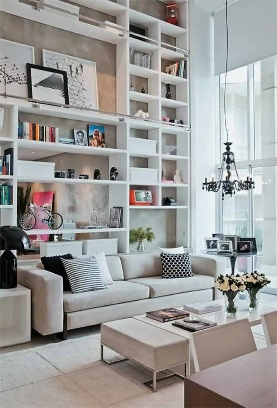 Grey and white living room with a tall shelving unit, neutral sofa, and stylish decorative accents.