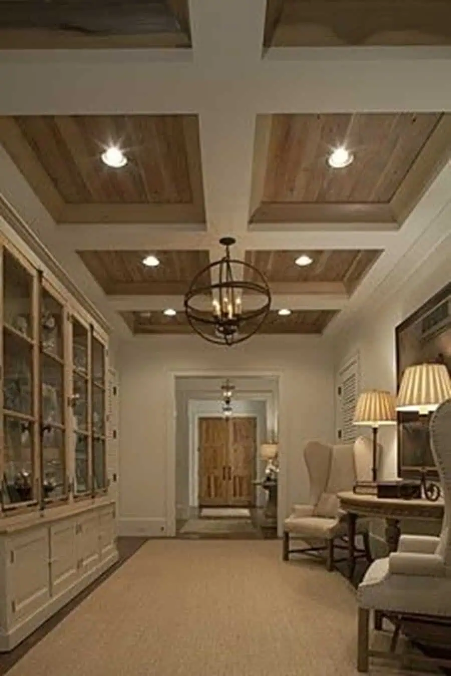 Elegant hallway with a modern coffered ceiling, wood accents, ambient lighting, and classic decor.