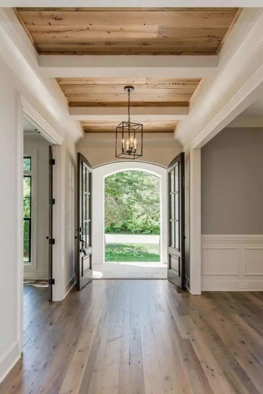 Elegant entryway with a modern coffered ceiling, wooden accents, double doors, and a lantern light.