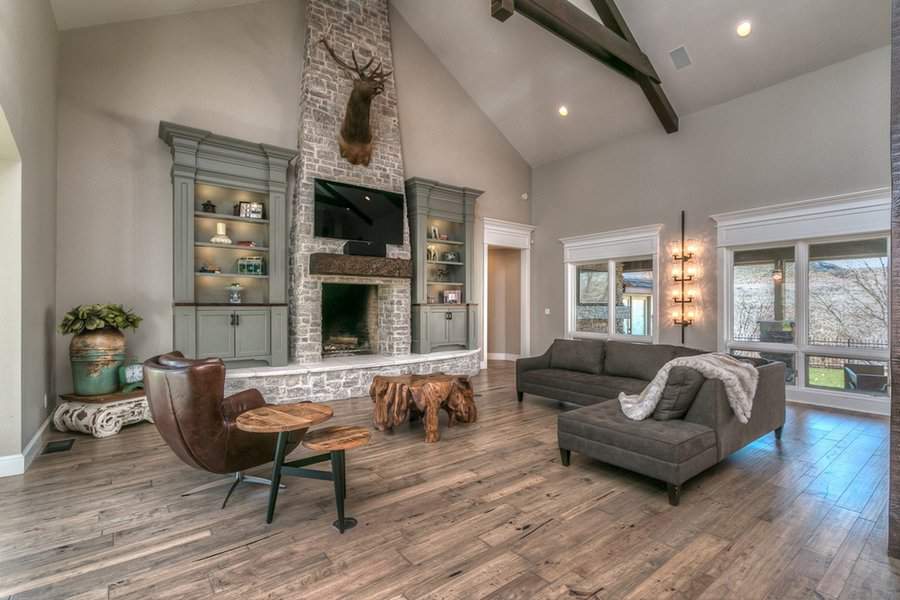Living room with built-in bookshelves featuring hidden storage, a stone fireplace, and cozy seating.