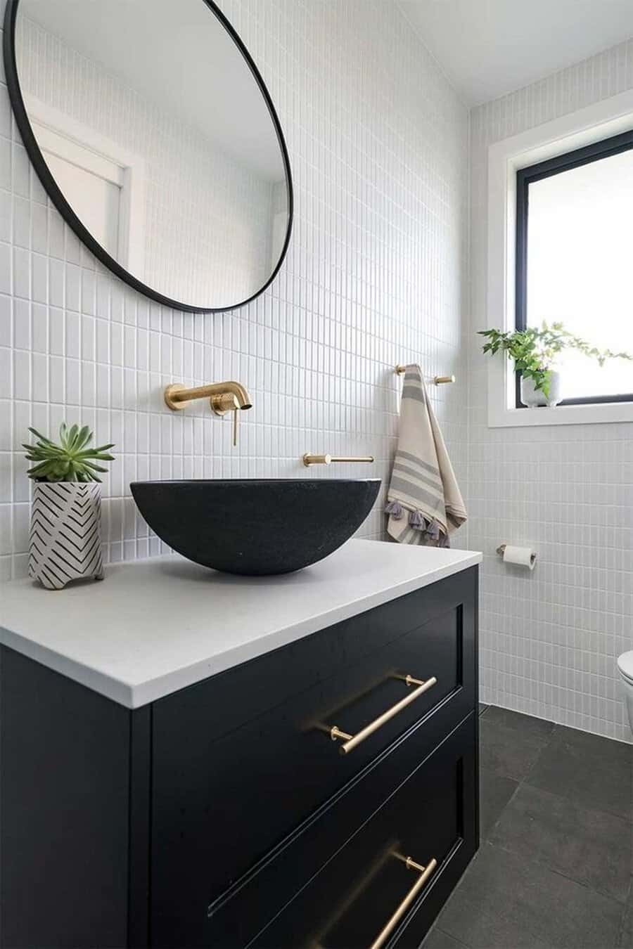 Black and white bathroom with a high-contrast vanity, vessel sink, and gold fixtures.
