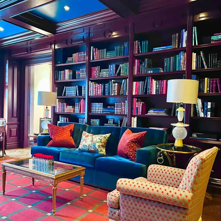 Home library with color-coded bookshelves, plush seating, and a sophisticated ambiance.