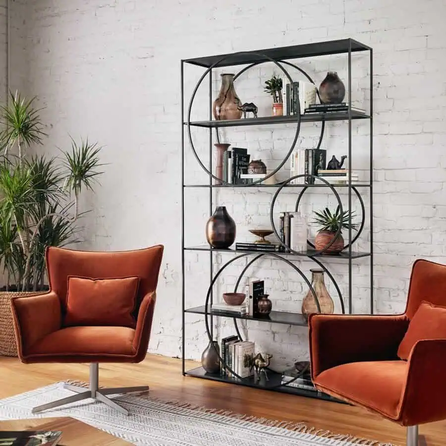 Industrial-style living room with a metal-framed bookshelf, modern decor, and bold accent chairs.