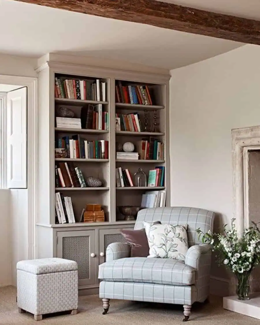 Classic living room with built-in bookshelves, a cozy plaid armchair, and rustic wooden beams.