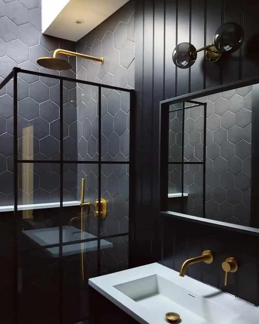 Loft-style black bathroom with hexagonal tiles, gold fixtures, and a sleek glass shower.